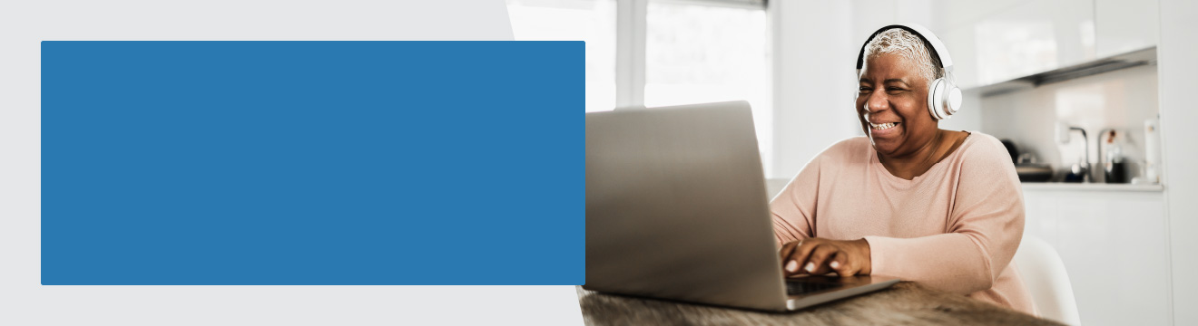 Lady with visual impairment using a laptop in her sunny kitchen.